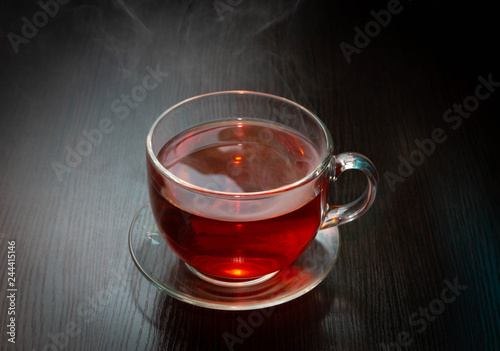 hot black tea in a Cup with steam over it on a dark wooden table