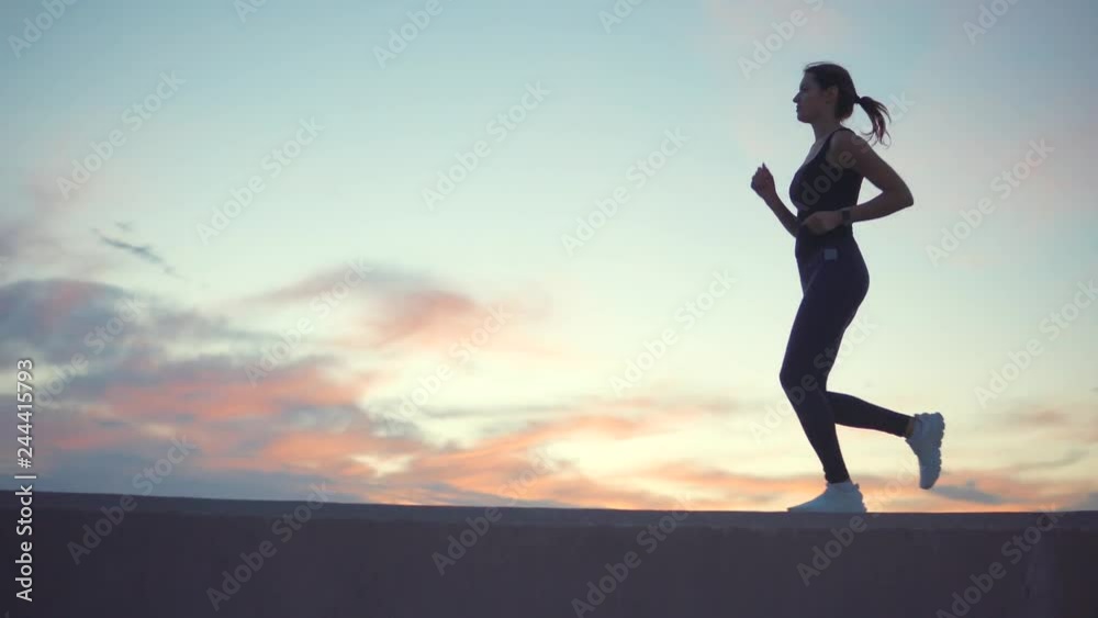 Young woman is running, figure against cloudy sky in sunset time Young woman is running, figure against cloudy sky in sunset time