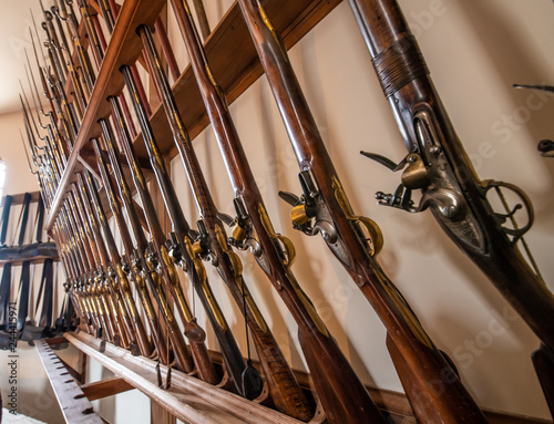 A row of old vintage antique muskets in a row in an armory