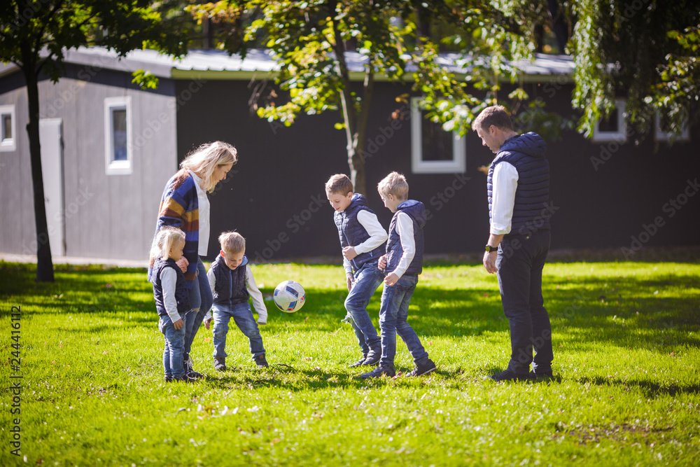 Fototapeta premium October 6, 2018 Ukraine. Kiev. theme family outdoor activities. big friendly Caucasian family six mom dad four children playing football, running ball on lawn, green grass lawn near house sunny day