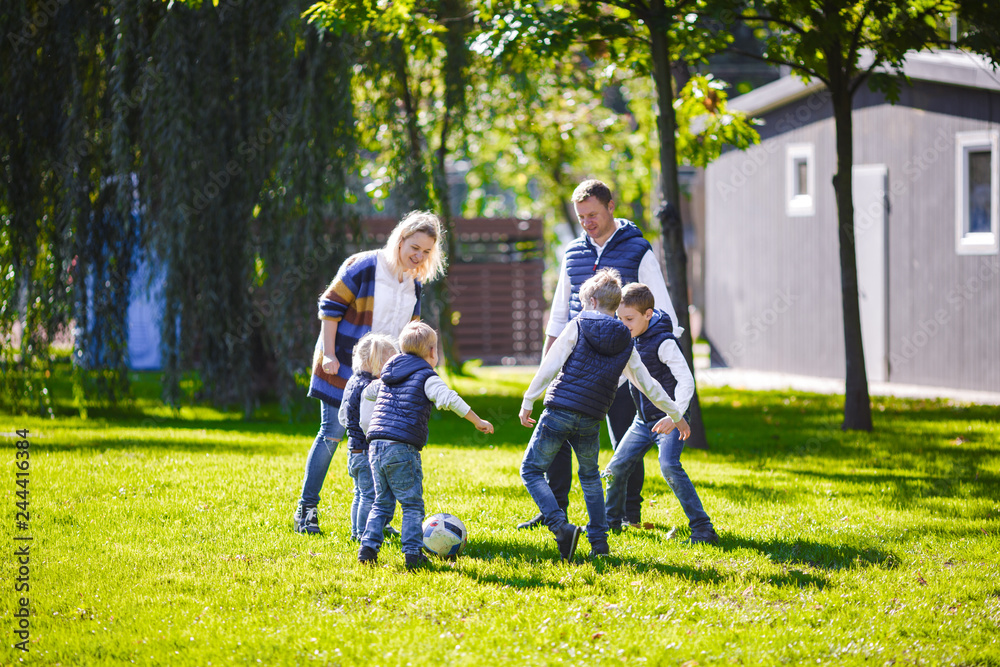 Fototapeta premium October 6, 2018 Ukraine. Kiev. theme family outdoor activities. big friendly Caucasian family six mom dad four children playing football, running ball on lawn, green grass lawn near house sunny day