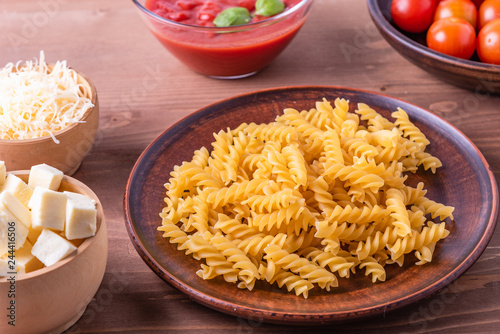 Fusilli pasta ingredients to prepare Italian dishes - pasta baked with mozzarella and tomato