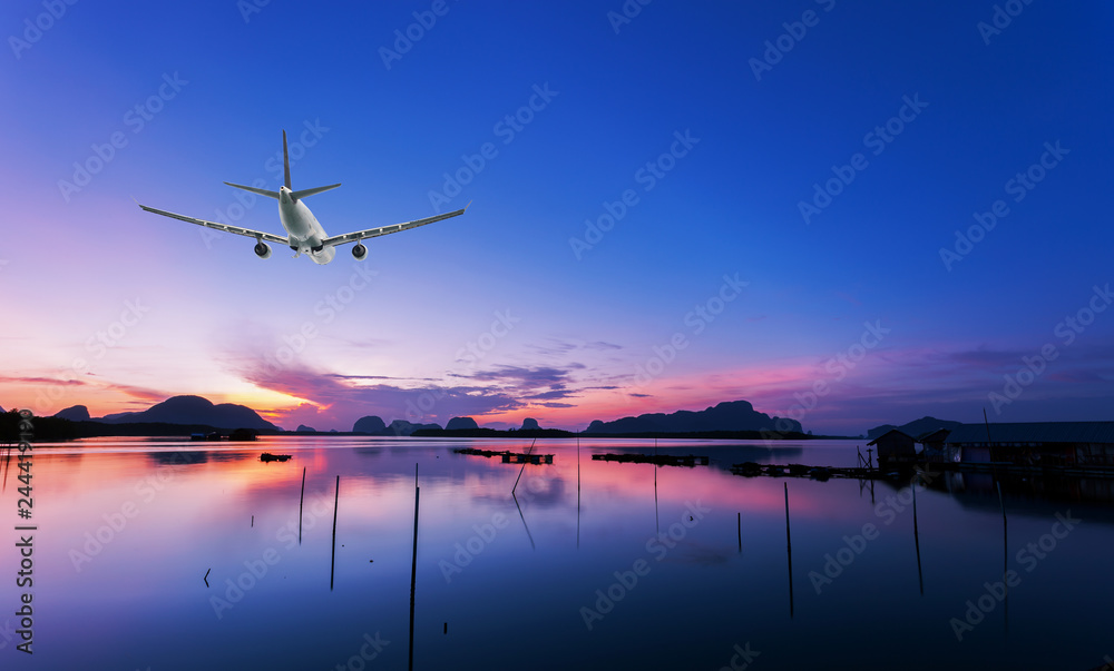 Airplane flying over tropical sea at beautiful sunset or sunrise scenery background.