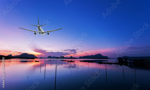 Airplane flying over tropical sea at beautiful sunset or sunrise scenery background.