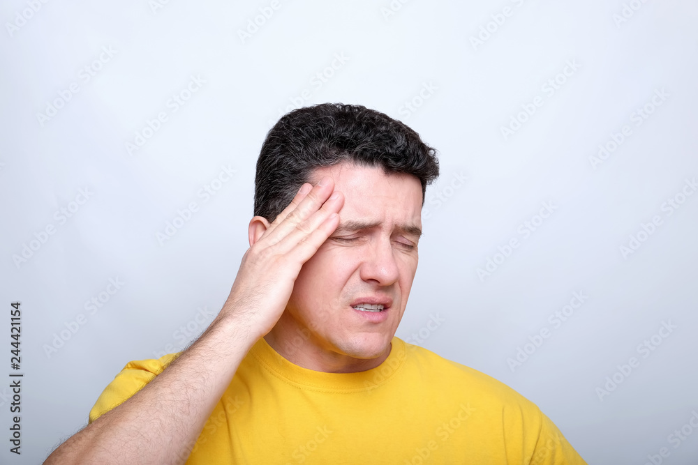 White middle-aged man with closed eyes, touches the head with one hand White middle-aged man with closed eyes, touches the head with one hand