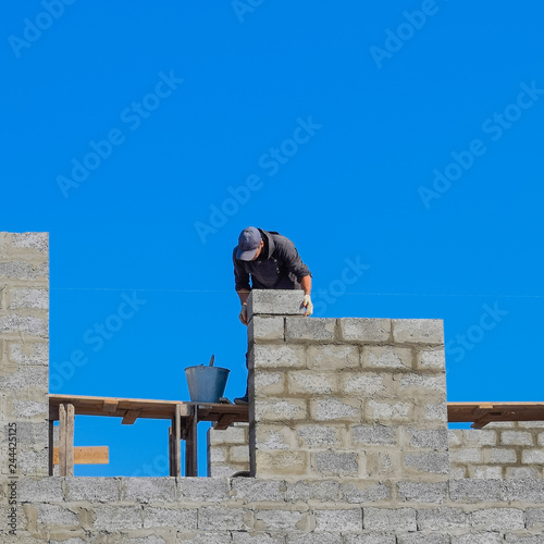 The builder builds the wall of the house from the cinder block.