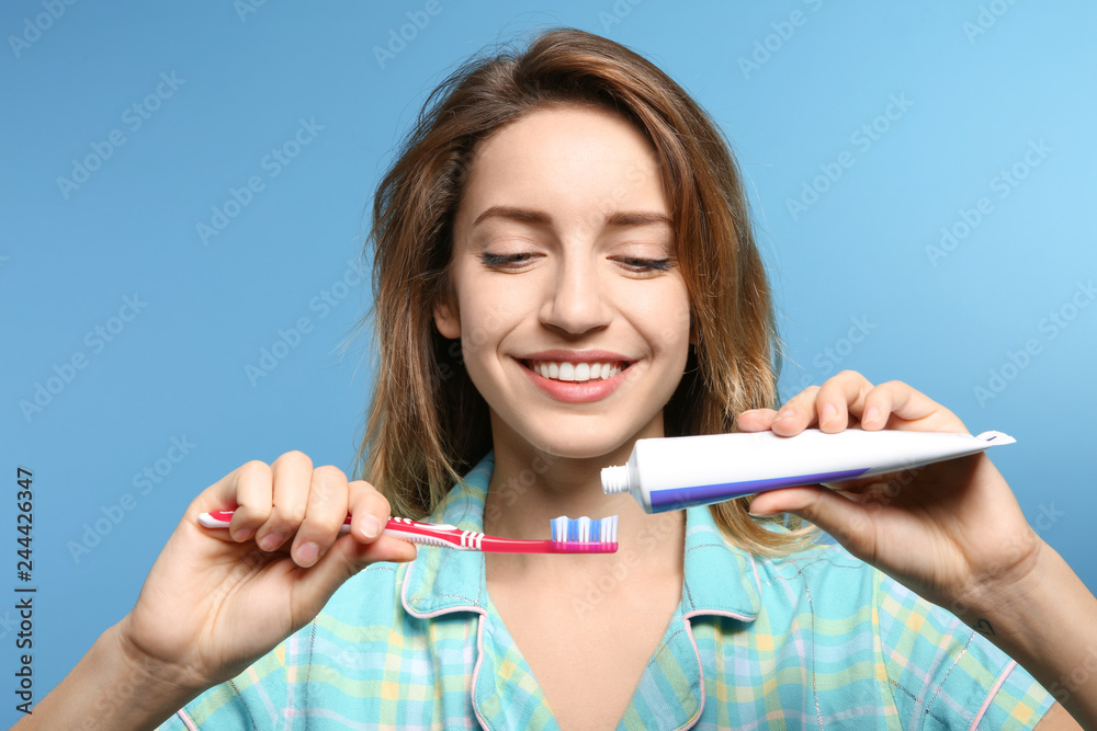 Portrait of young woman with toothbrush and paste on color background Portrait of young woman with toothbrush and paste on color background