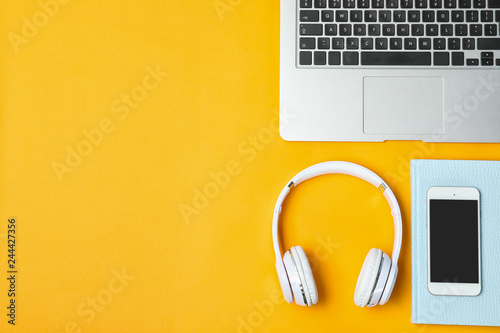 Flat lay composition with headphones, smartphone, laptop and space for text on color background