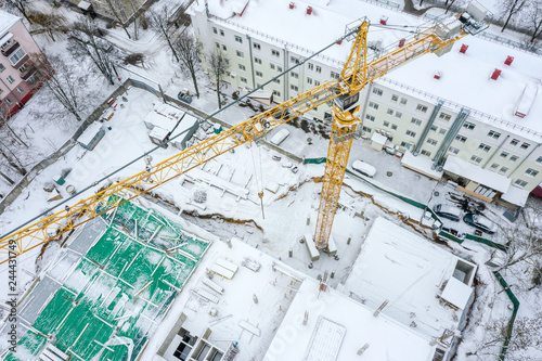 aerial top view of tall tower crane working at construction site in winter. drone photography