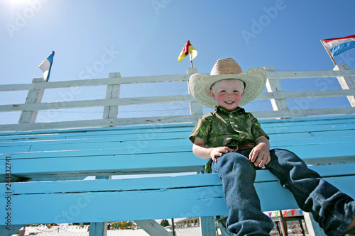 Photography A young boy wearing a cowboy hat, sitting in the bleachers at a county fair rodeo