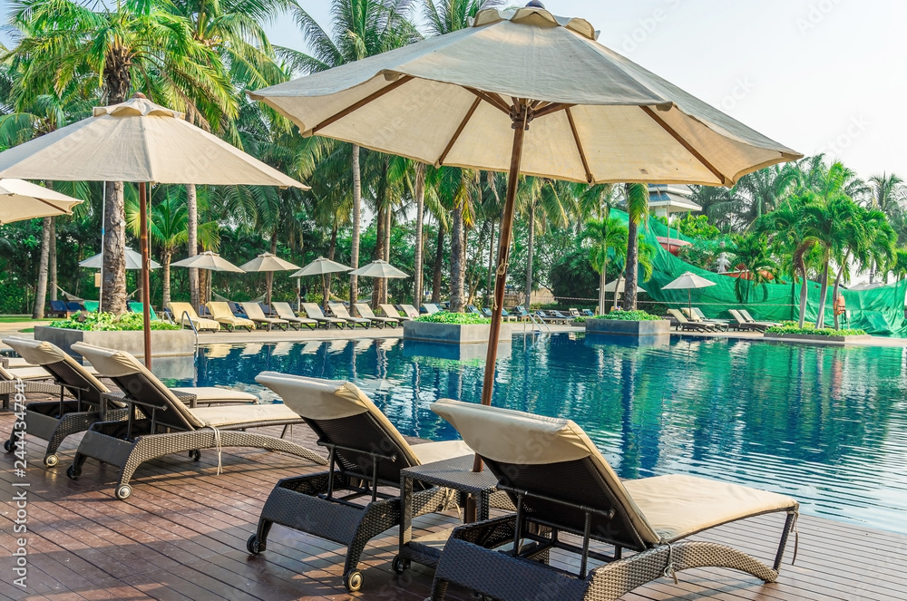 Relaxing rattan chairs with pillows beside swimming pool
