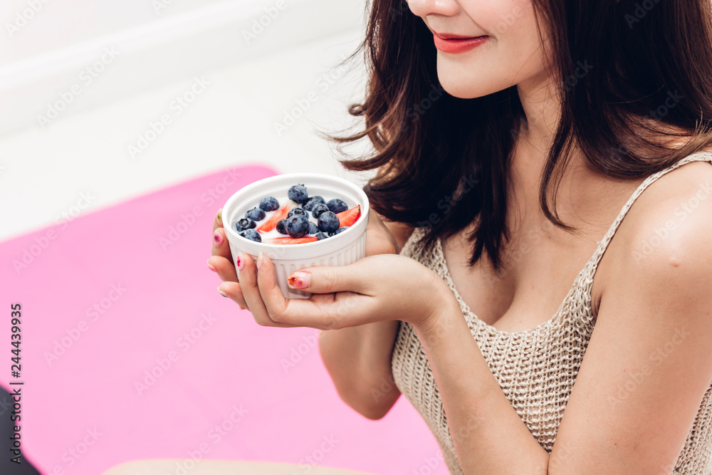 Fitness woman holding yogurt and mixed berries blueberries with strawberries while relaxing at home.dieting concept.healthy lifestyle Fitness woman holding yogurt and mixed berries blueberries with strawberries while relaxing at home.dieting concept.healthy lifestyle