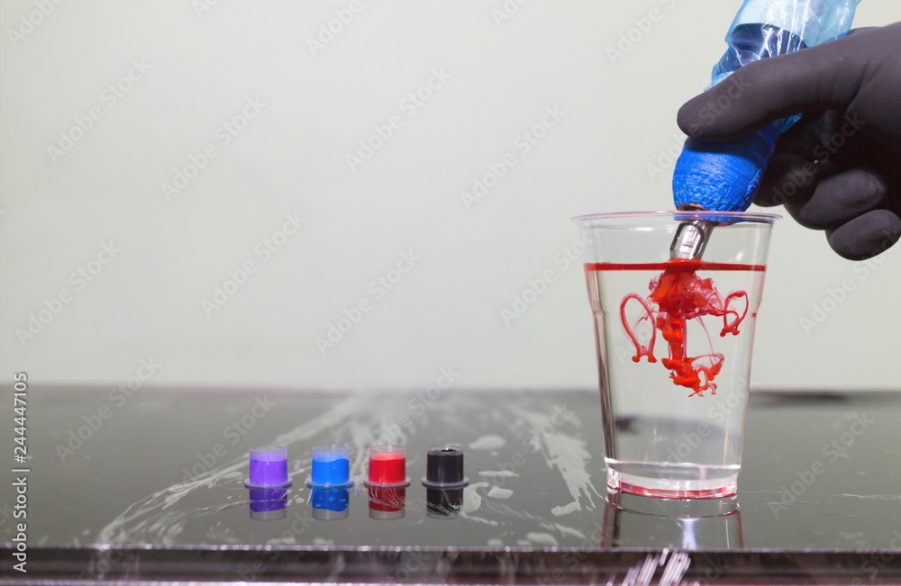 Φωτογραφία Tattoo artist holding a tattoo machine on hand and tattoo ink in caps on the table in tattoo studio