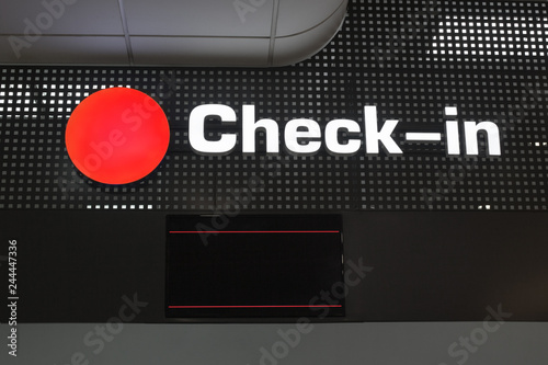 Check in desk at international airport, checkin counter and monitor for flight information display, red round sign close up, layout for passenger air transportation and flight ticket registration photo