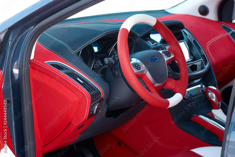 Steering wheel. Car dashboard. Car interior details. Red and black alcantara with stitching