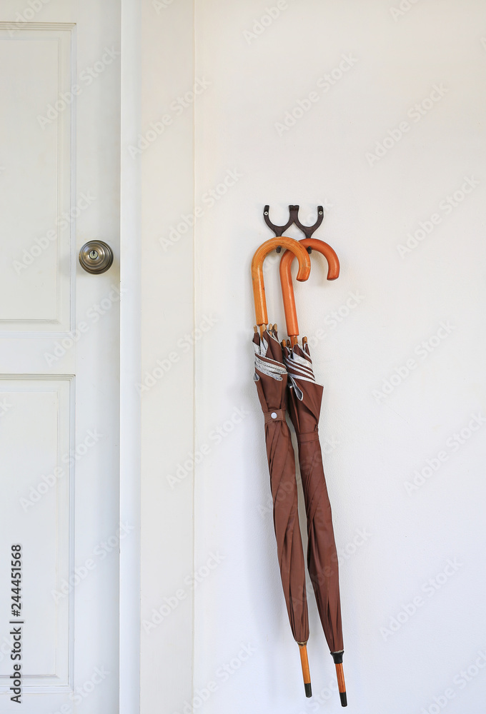 Obraz premium Umbrellas hanging in front of wood door room. Ready to be picked up during rain.