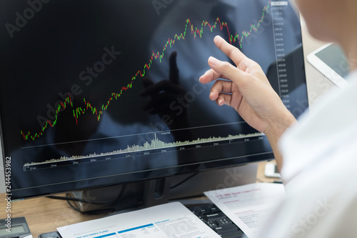 Stock exchange trader Analyzing Graphs chart or data On Multiple Screens in office Fototapet