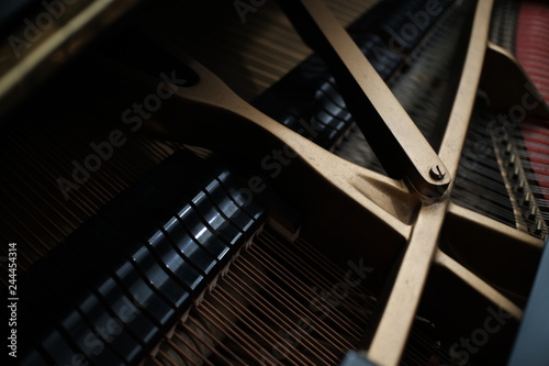  internal parts of an upright piano strings and a tuning key on the pins. © Charlie's