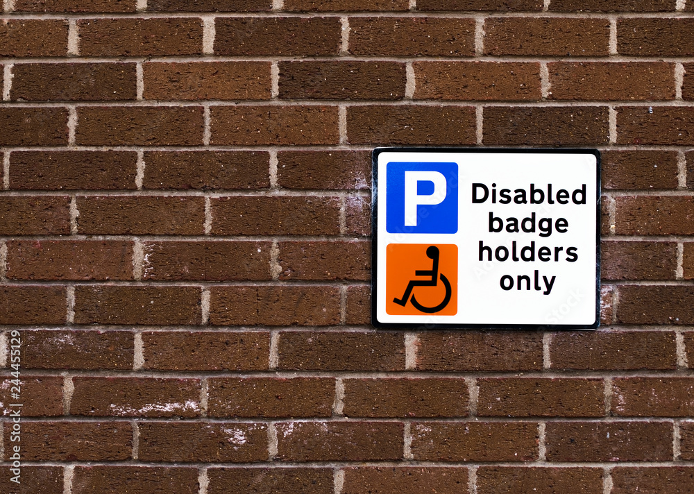 Disabled badge holders only sign on a brick wall Disabled badge holders only sign on a brick wall