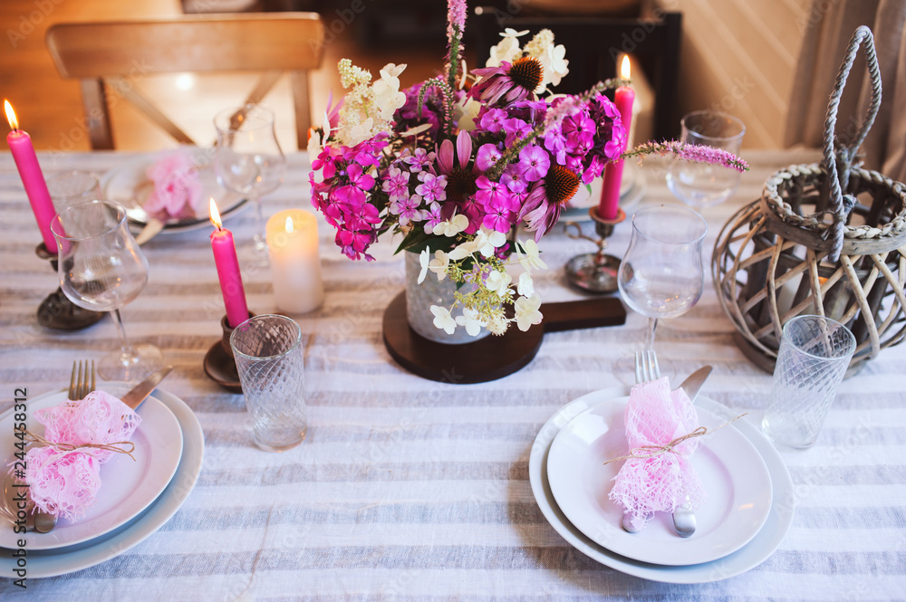 details of summer festive table with candles and seasonal flowers. Table setting for romantic dinner in cozy country house