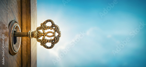 Old key in keyhole on sky background with sun ray . Concept, symbol and Idea for History, business, security, religion background. photo