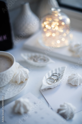 White flatlay styling  cup of coffee  bell jar with lights and jewelry