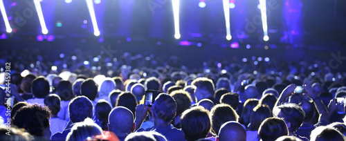 people at live concert with blue lights and spotlights on the stage