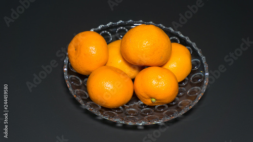 Several fresh mandarin on a plate on a black background