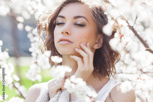 Close up portrait of young beautiful woman on spring background. Attractive young girl with flowers. Spring make up model.