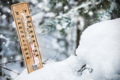 thermometer with subzero temperature stuck in the snow in the winter forest