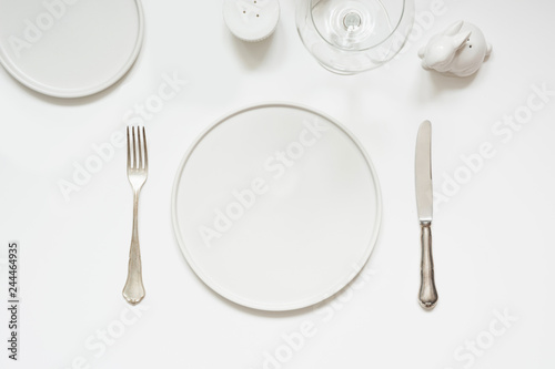 Festive modern white table setting. Plates and cutlery on white. View from above.