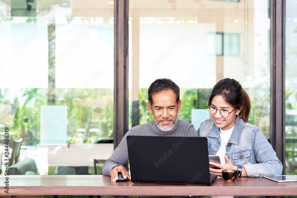 Attractive mature asian man with white stylish short beard looking at laptop computer with teenage eye glasses hipster woman in cafe. Teaching internet online or wifi technology in older man concept. Attractive mature asian man with white stylish short beard looking at laptop computer with teenage eye glasses hipster woman in cafe. Teaching internet online or wifi technology in older man concept.