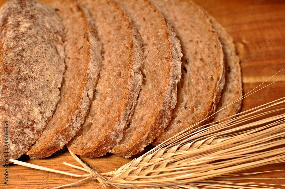 Top table of slices of brown cereal healthy bread with dried wheat decoration on wooden table background Top table of slices of brown cereal healthy bread with dried wheat decoration on wooden table background
