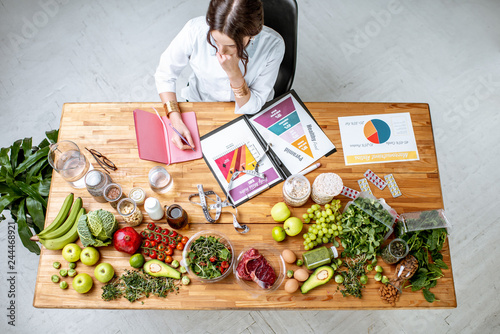 Dietitian writing diet plan, view from above on the table with different healthy products and drawings on the topic of healthy eating
