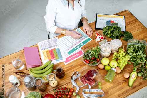 Dietitian writing a diet plan, view from above on the table with different healthy products and drawings on the topic of healthy eating