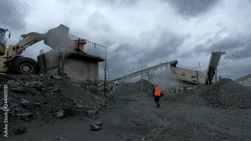A huge excavator is digging black coal at the coal mine with workers in orange robes on the background photo
