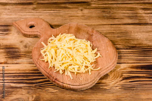 Cutting board with grated cheese on wooden table