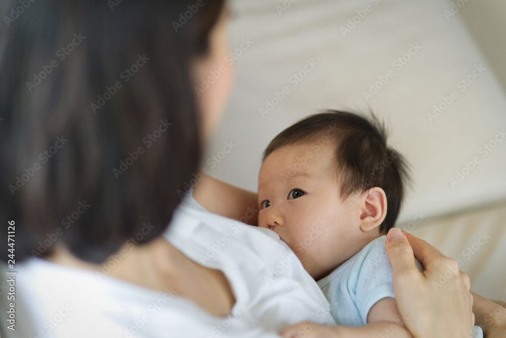 Young beautiful Asian mother sitting and holding her newborn child