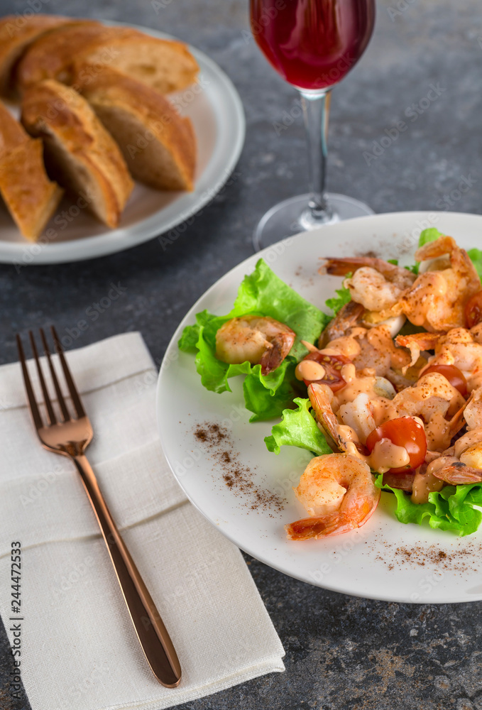 salad with Royal prawns on a white plate on the dark surface of the table with Cutlery. salad with Royal prawns on a white plate on the dark surface of the table with Cutlery.