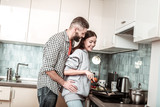 Loving husband hugging his girlfriend cooking breakfast for him
