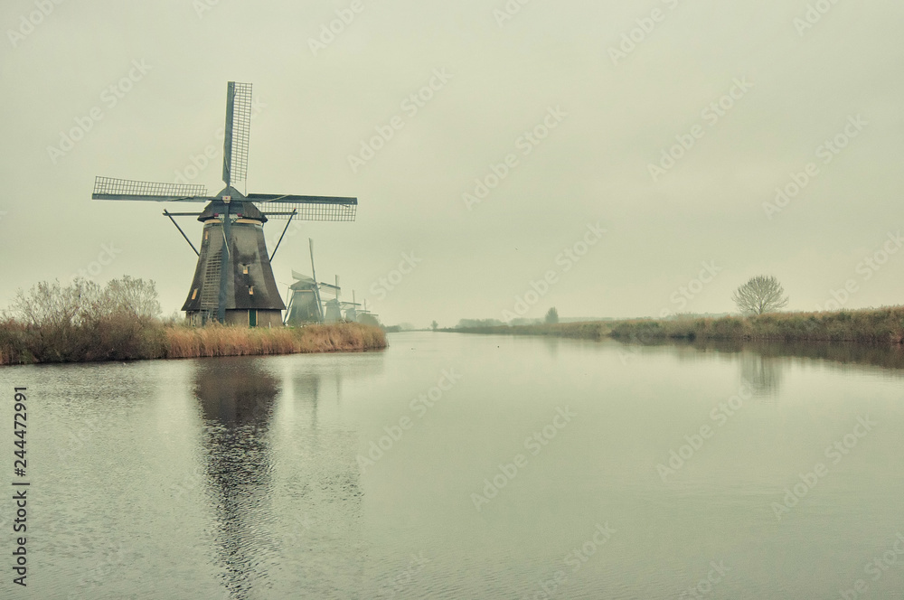 The Famous Netherlands wooden Windmills, UNESCO World Heritage Site, Kinderdijk Windmill village in the soft sunset light of winter with vintage style.