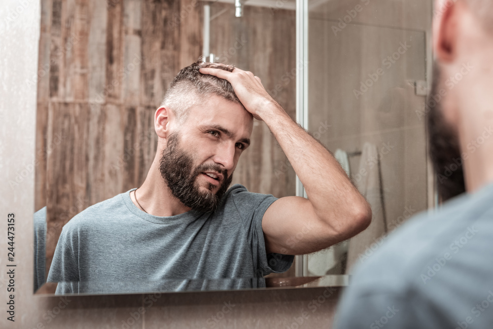 Obraz premium Handsome bearded dark-eyed businessman fixing his hair