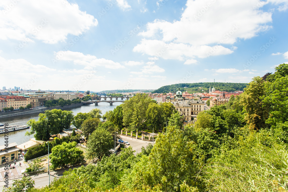 Scenic view of bridges on the Vltava river and of the historical center of Prague: buildings and landmarks of old town with red rooftops and multi-coloured walls.