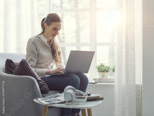 Young woman sitting next to a window and connecting with her laptop Free Download Young woman sitting next to a window and connecting with her laptop - GFXLoad