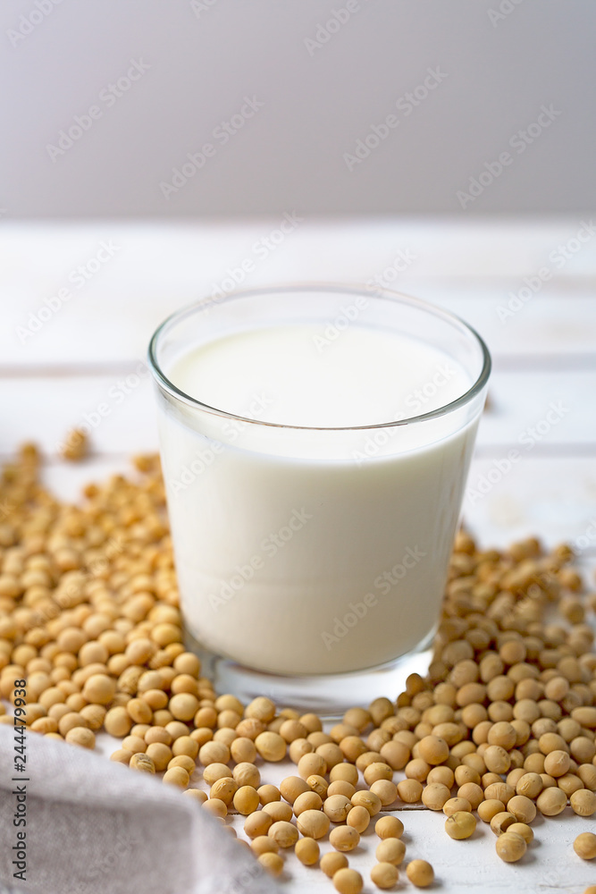Raw soy seeds and glass of milk on slate background. Organic farming Raw soy seeds and glass of milk on slate background. Organic farming