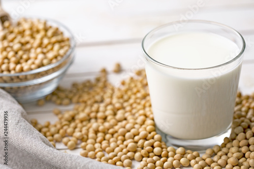 Raw soy seeds and glass of milk on slate background. Organic farming