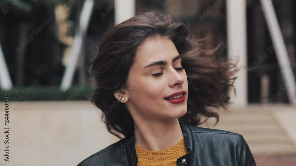 Happy young woman walking on the street, looking and posing into the camera. Beautiful girl moving in dance. Slow motion
