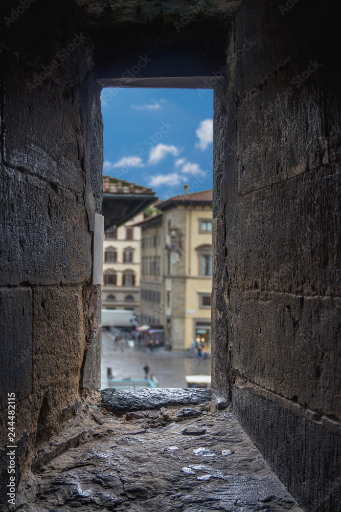 narrow stone window in the fortress wall overlooking the houses of the old Italian city of Florence