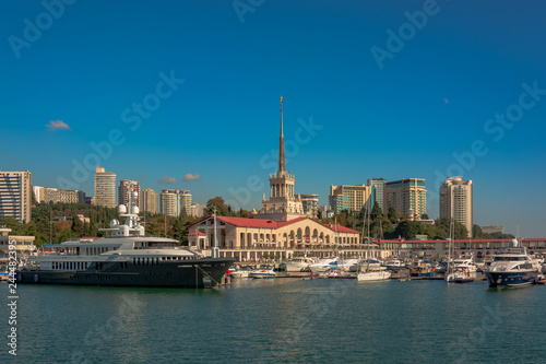 Sea port in summer. Many different yachts and boats stand at the marina. Yachtsmen and travelers are preparing to sail in the sea. In the background of the building of the seaside city.