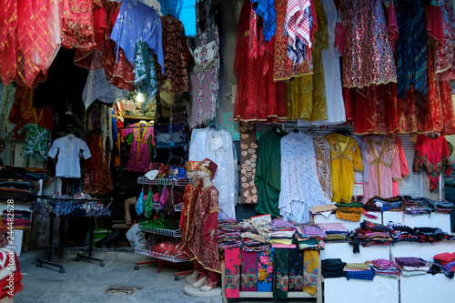 Rolls of fabric and textiles for sale stacked on shelves in shop, scarves for sale at the market, Traditional turkish, kurdish, arabic women dresses and costumes for sale at a market